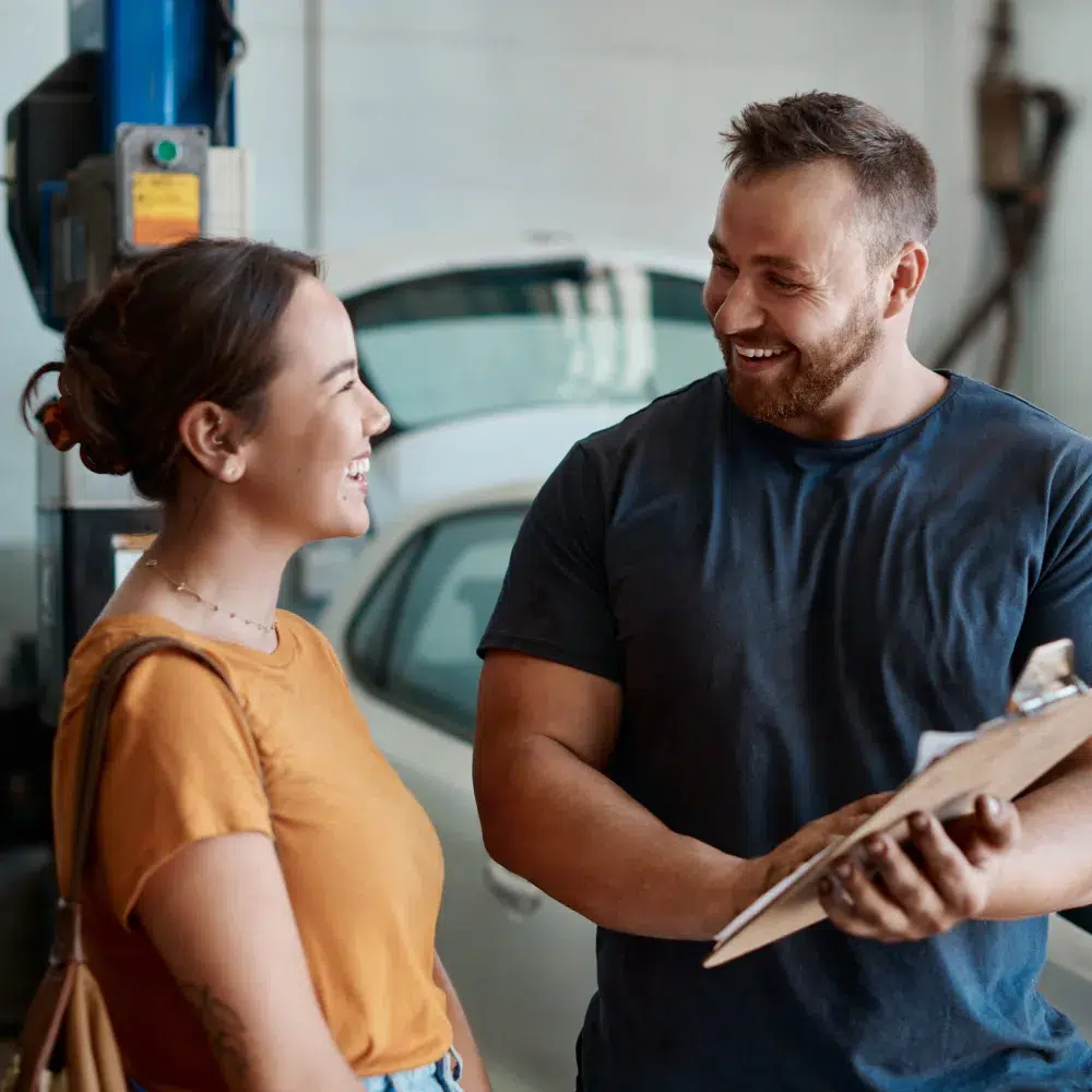 Deux personnes souriantes discutant dans un garage